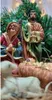 A close-up of a nativity scene with figurines of Mary, Joseph, and baby Jesus, along with a lamb, set against a backdrop of a Christmas tree and lights. Produktbild-Vorschau
