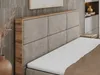 A close-up view of a bed with a beige upholstered headboard and a wooden frame, featuring a white mattress topper. Produktbild-Vorschau