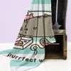 A Pusheen blanket with a cartoon design is draped over a wooden crate. Produktbild-Vorschau