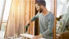 A man is using a green power drill to attach a piece of wood to another piece of wood. Podgląd zdjęcia produktu