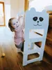 A young child is climbing on a white learning tower with a panda face design. Anteprima dell’immagine prodotto