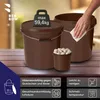 Two brown buckets are shown on a wooden surface. One bucket has a weight icon on its lid, and the other has a hand wiping it with a cloth. A smaller bucket filled with garlic is in front of the larger buckets. Text and icons are displayed in the bottom sec Voir les images du produit