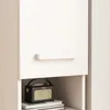 A close-up view of a white cabinet with a handle and a small black radio on a shelf below. Náhľad obrázku produktu