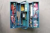 A blue metal toolbox filled with various tools, laid out on a gray concrete surface. Produktbild-Vorschau