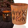 Two rusty metal fire baskets with flame cutouts, one lit with a candle inside, placed on a brick patio with autumn leaves in the background. Produktbild-Vorschau