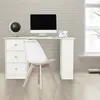 A white desk with a computer, globe, and a small sign with text, in a room with a brick wall and a window. Produktbild-Vorschau