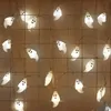 A string of ghost-shaped Halloween lights are draped over a grid-like surface. Produktbild-Vorschau