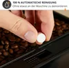 A hand holding a cleaning tablet over a coffee bean grinder. Podgląd zdjęcia produktu