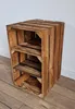 A rustic wooden crate shelf unit with three shelves, standing on a wooden floor against a white wall. Produktbild-Vorschau