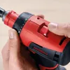 A person's hands are holding a red and black power drill. Voir les images du produit