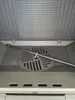 Interior view of a stove or fireplace with a metal grate and a long metal rod. Náhled obrázku produktu