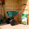 A garden spreader and bag of fertilizer are shown inside a wooden shed. Produktbild-Vorschau