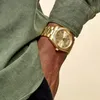 A close-up shot of a person's arm wearing a gold watch. Anteprima dell’immagine prodotto