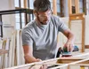 A man is sanding a wooden frame in a workshop. Anteprima dell’immagine prodotto