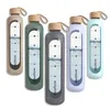 A group of five glass water bottles in different colors, each with a silicone sleeve and a bamboo lid. The bottles have measurement markings and a water level indicator. Náhľad obrázku produktu