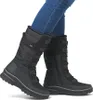 A person wearing black winter boots and blue jeans, shown from the knees down. Produktbild-Vorschau