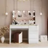 A modern vanity table with a lighted mirror, makeup, and a stool in a bedroom. Produktbild-Vorschau