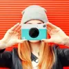 A person holding a camera in front of their face against a red background. Anteprima dell’immagine prodotto