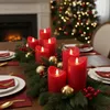 A festive Christmas table setting with red LED candles, evergreen branches, and gold ornaments. Produktbild-Vorschau