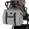 A gray diaper bag is attached to the handle of a stroller. Náhľad obrázku produktu