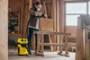 A person is using a sander with a vacuum attachment in a workshop. Anteprima dell’immagine prodotto