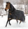 A horse wearing a black turnout rug with gold trim runs through snow. Voir les images du produit