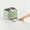 A hand is pulling out a crumb tray from a green toaster. Produktbild-Vorschau