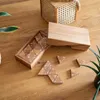 A wooden puzzle game with triangular pieces numbered 1-6 is laid out on a wooden table next to its wooden storage box. A woven basket is in the background. Podgląd zdjęcia produktu