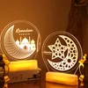 Two illuminated Ramadan-themed decorative lights are displayed on a surface, with a book and decorative lanterns in the foreground. Produktbild-Vorschau