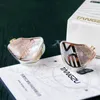 Two in-ear monitor headphones are displayed on a white surface with a dark green background. A white box with the brand name is visible in the background. Produktbild-Vorschau