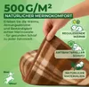 A hand holding a folded brown and beige plaid wool blanket with green text overlays describing its features. Produktbild-Vorschau
