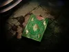 A green and gold deck of playing cards is placed on a textured, rocky surface with dramatic lighting. Náhled obrázku produktu
