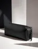 A black accessory case is placed on a white surface with a black and white background. Voir les images du produit