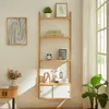 A wooden ladder shelf with decorative items and storage compartments, placed against a white wall next to a window. Voir les images du produit