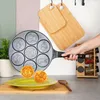 A hand holding a multi-mold pancake pan with animal shapes, with two finished pancakes on a plate in the foreground. Anteprima dell’immagine prodotto