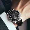 A close-up shot of a man's wrist wearing a black leather strap watch with a complex black dial. Produktbild-Vorschau