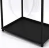 Close-up view of the bottom shelf and legs of a black metal firewood rack. Produktbild-Vorschau