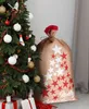 A Christmas sack decorated with stars and the text "Merry Christmas" stands next to a decorated Christmas tree. Produktbild-Vorschau