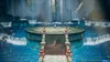 A scene from a video game with characters standing on a circular platform surrounded by waterfalls. Produktbild-Vorschau