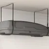 A gray roof box is suspended from the ceiling by straps. Voir les images du produit