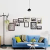 A living room scene with a blue sofa, a coat rack, and a collection of framed pictures on the wall. Produktbild-Vorschau