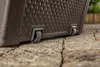 A close-up view of the bottom of a brown storage box with wheels, resting on a stone patio. Podgląd zdjęcia produktu