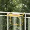 A yellow balcony table is attached to a white railing, with books and a drink on it. Trees and a white fence are visible in the background. Anteprima dell’immagine prodotto