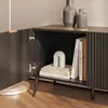 Close-up view of an open cabinet door of a black media console, revealing books and a decorative object on a shelf. Podgląd zdjęcia produktu