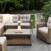 An outdoor lounge set with a coffee table on a patio, surrounded by greenery. Náhľad obrázku produktu