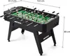 A black foosball table with green playing field and white and black player figures, shown on a white background with dimensions indicated. Náhled obrázku produktu