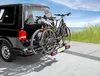 A black van with two bicycles mounted on a rear rack, parked near a beach. Produktbild-Vorschau