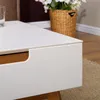 A close-up shot of a white coffee table with a wooden drawer. Produktbild-Vorschau