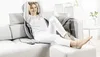 A woman is relaxing on a couch with a massage cushion. Voir les images du produit