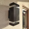 A black and clear outdoor wall light mounted on a textured wall next to a window. Náhľad obrázku produktu